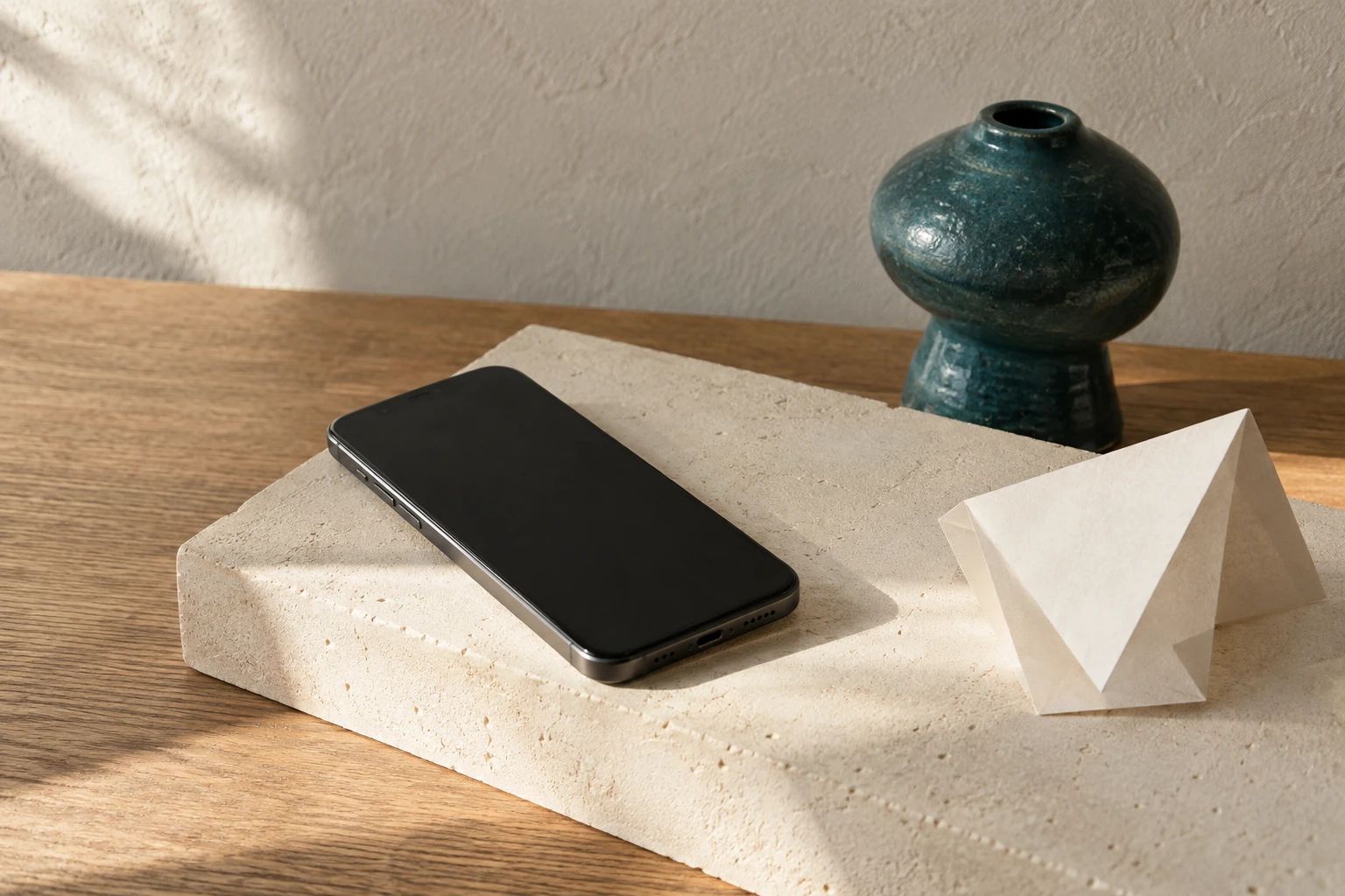 A graphite phone and folded paper prototype on a cream plaster block.